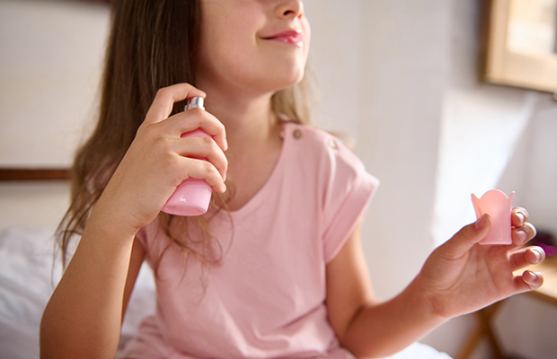 A young girl spraying perfume