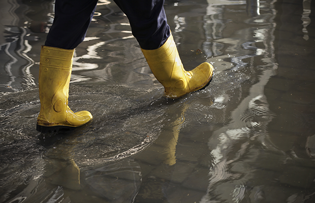 A closeup of a person wearing yellow rainboots, they're walking on an area that has water