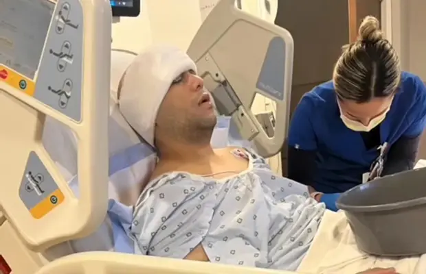 A man laying on a hospital bed, there's a medical professional near him