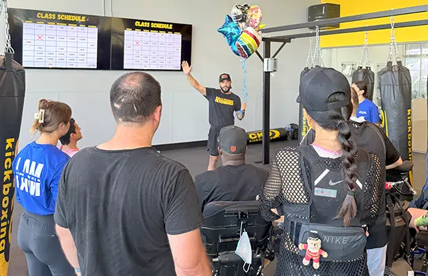 A group of people looking at a man who is going over a kickboxing routine