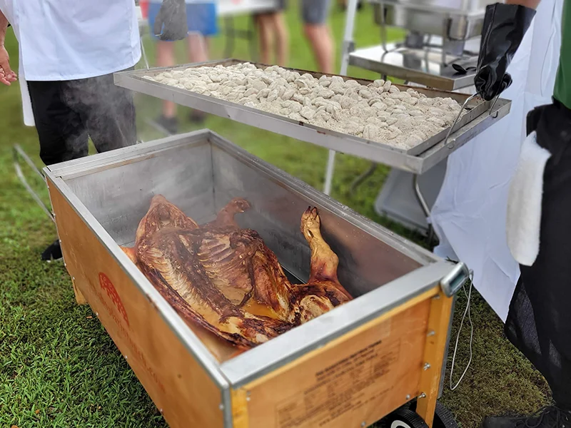 Closeup of people closing a box that has a pig being cooked