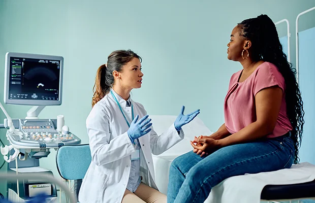 Medical professional sitting and speaking to a patient who is sitting across them
