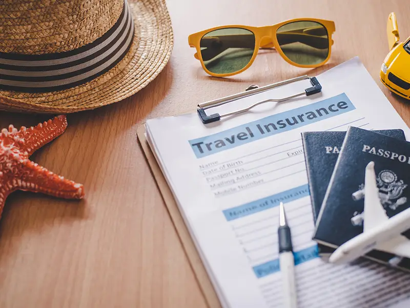 A table with a few items on it; a hat, check list, passport, sunglasses, small model airplane