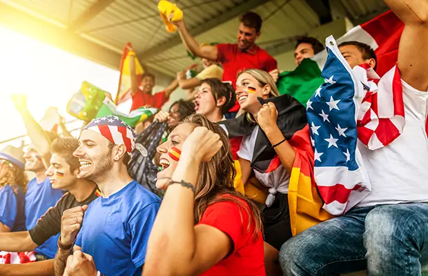 A crowd of people sitting at a sporting event and rooting for their team, they have USA colors and attire on