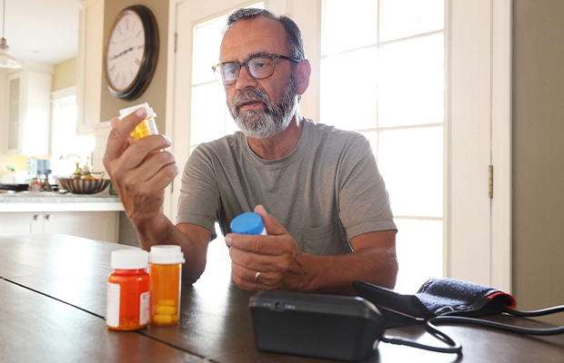 A man sitting on his dinning room checking his medicines