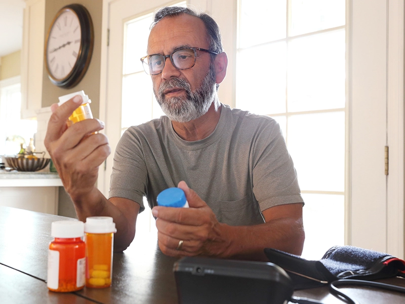 A man sitting on his dinning room checking his medicines