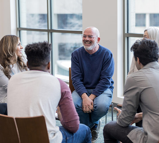 A group of adults sitting around in a circle during a support group session
