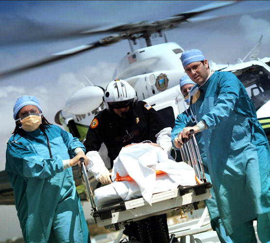 A team of doctors outside of an emergency helicopter bringing a patient on a gurney into the hospital