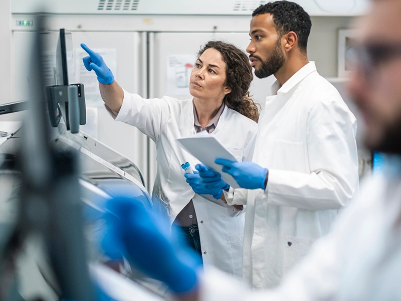 Three people examining X-rays in a laboratory, dressed in lab coats and nursing gloves.