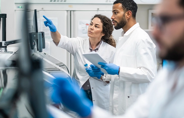 Three people examining X-rays in a laboratory, dressed in lab coats and nursing gloves.