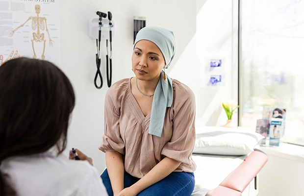 Woman wearing headscarf sitting on hospital gurney talking with her doctor