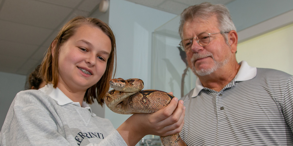 Brian Mealey next to a young girl who is holding a snake