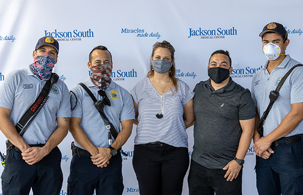Three medical professionals, a men, and woman, wearing face masks and taking a picture