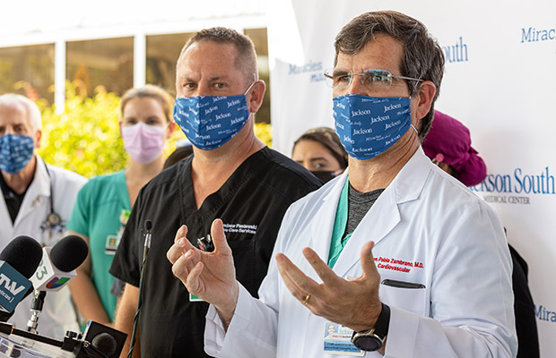 Medical professionals at an event speaking to the media, a medical wearing a white coat is speaking