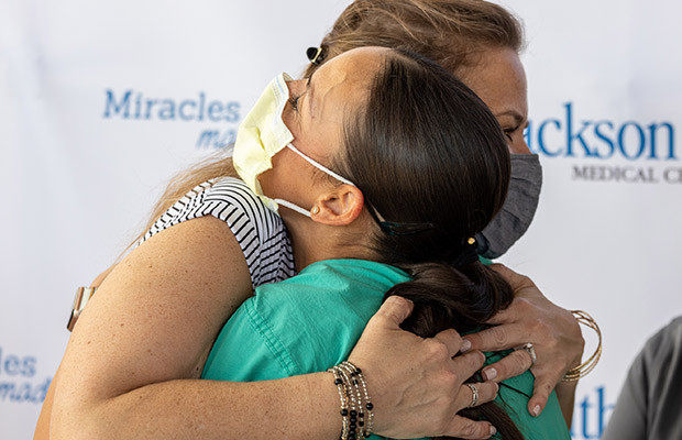 Women wearing a mask hugging a medical professional who is also wearing a face mask