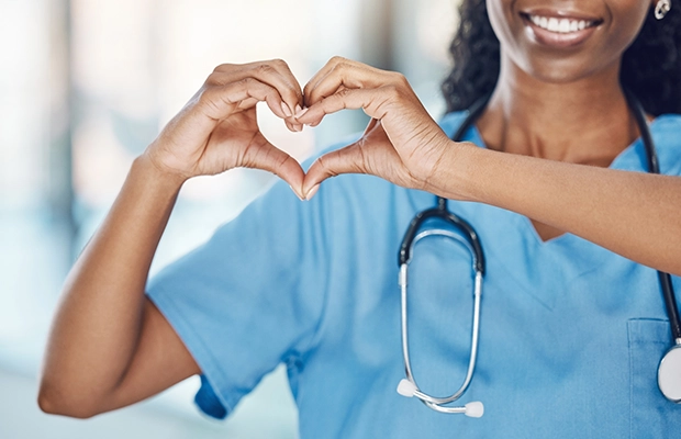 Close-up of a woman's hands making a heart shape.