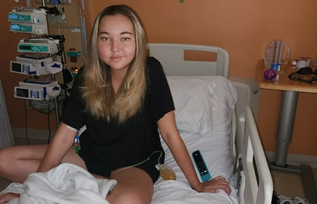 Young woman sitting on a hospital gurney.