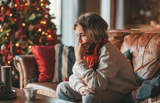 Woman sitting on sofa in front of cup of tea with Christmas decoration