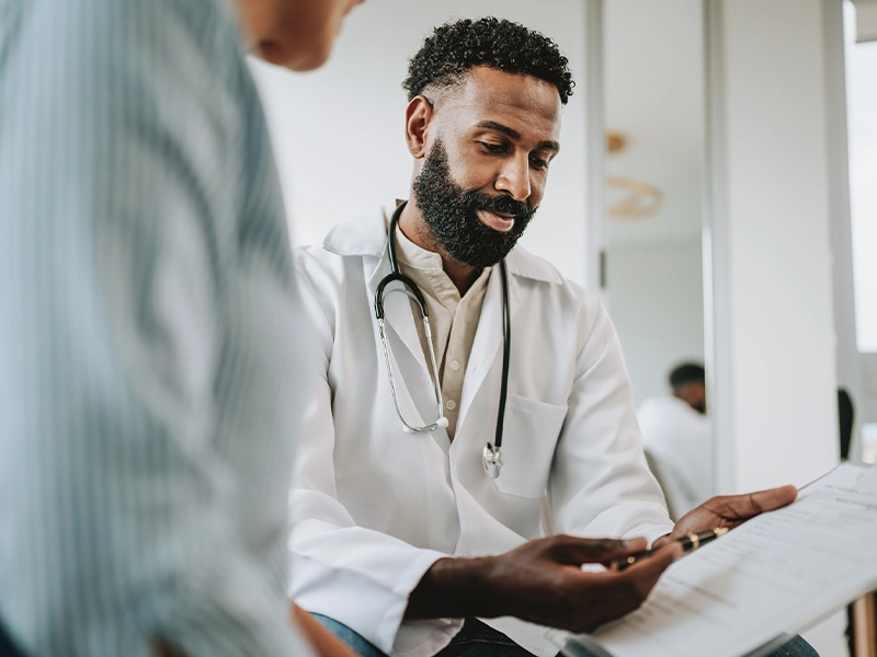 An image of a person seen from behind talking to a doctor.