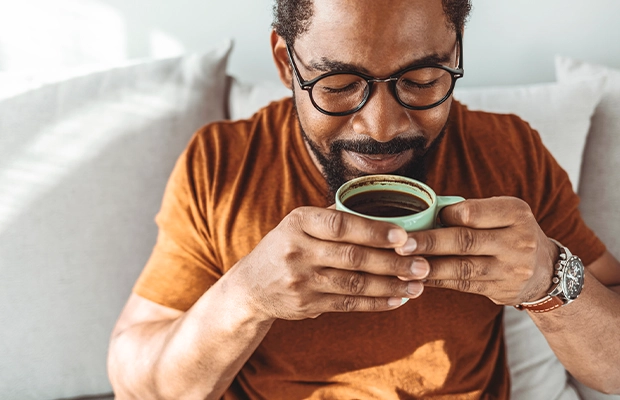 Man in a caramel-colored t-shirt drinking coffee