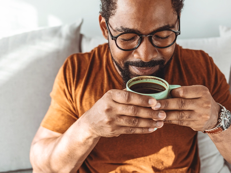 Man in a caramel-colored t-shirt drinking coffee