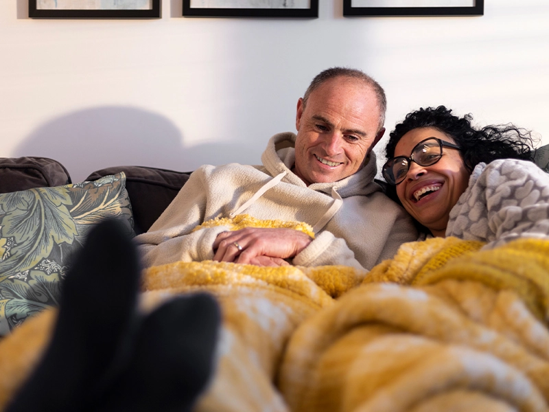 A couple lying in bed, covered with a yellow blanket