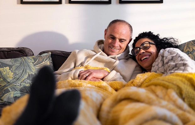 A couple lying in bed, covered with a yellow blanket