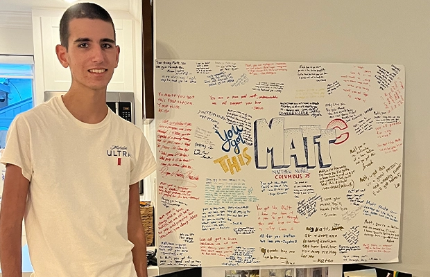 young man next to poster full of message from his friends