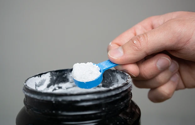 Close-up of a hand scooping protein from a jar