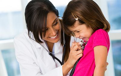 Female doctor examining a little girl while smiling