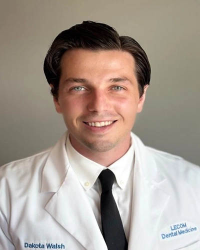 Professional headshot of Dakota-M, a man smiling, against a white studio background