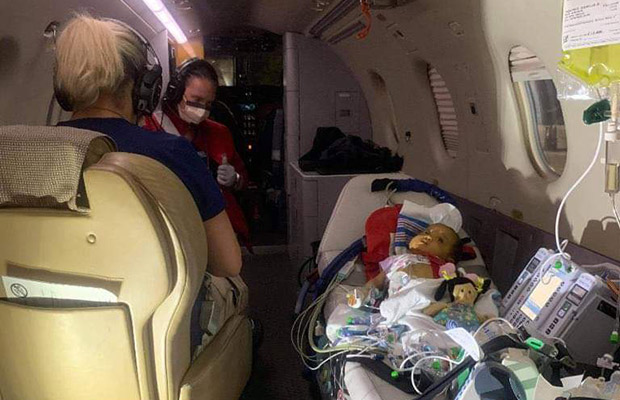 Baby in a flight with medical devices and two medical professionals