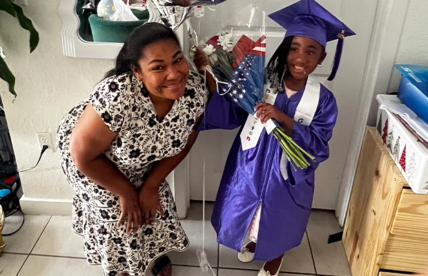 Photograph of a mother with her young daughter who is holding balloons.