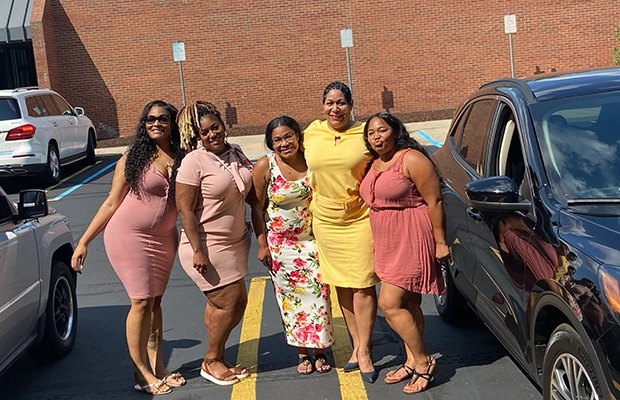 Five elegantly dressed women posing and smiling at the camera
