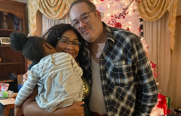 A couple smiling and posing while holding their daughter