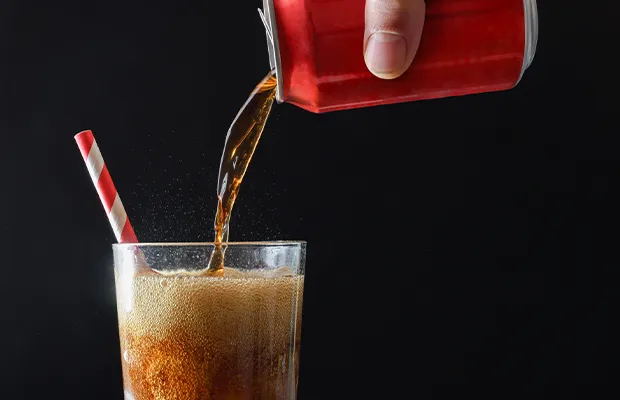 Close-up of a hand pouring a soda into a glass
