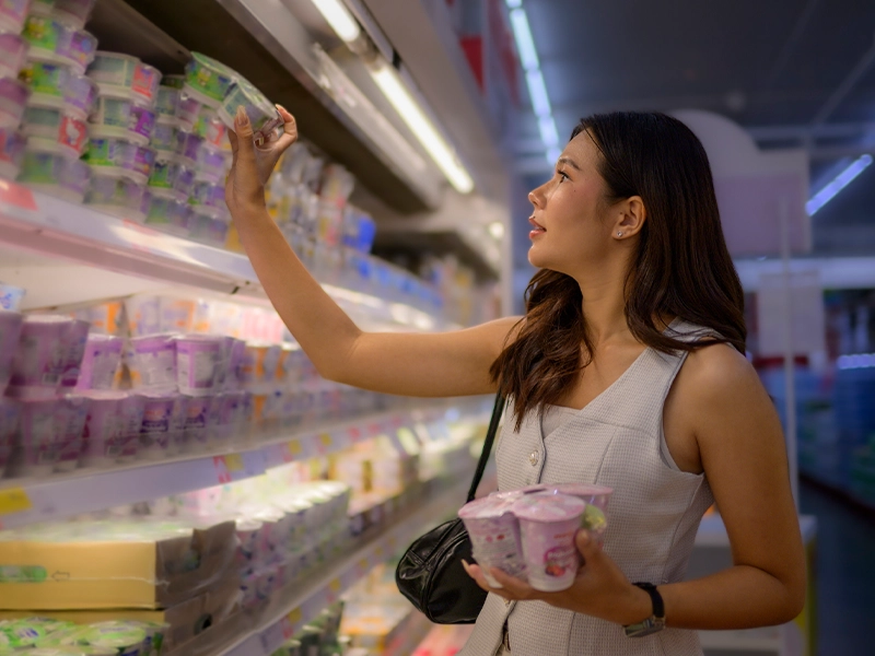 woman selecting products from a supermarket refrigerator