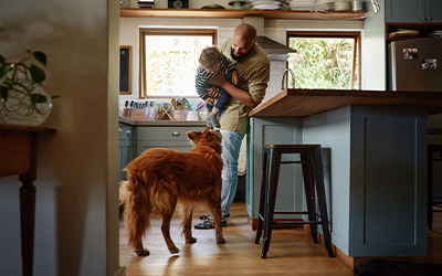 dad holds up his son in front of a dog