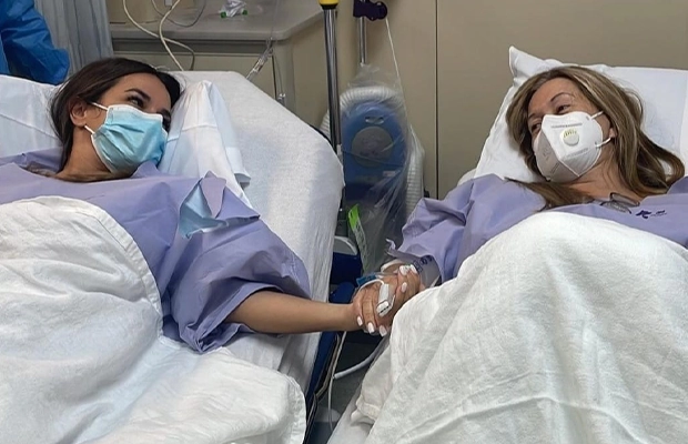 Two women lying on a hospital gurney looking at each other