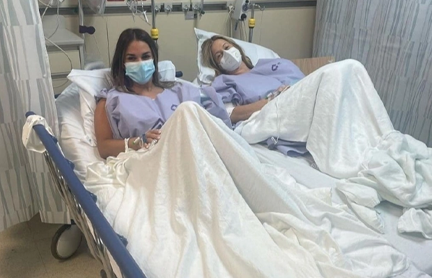 Two women lying on a hospital gurney looking at each other