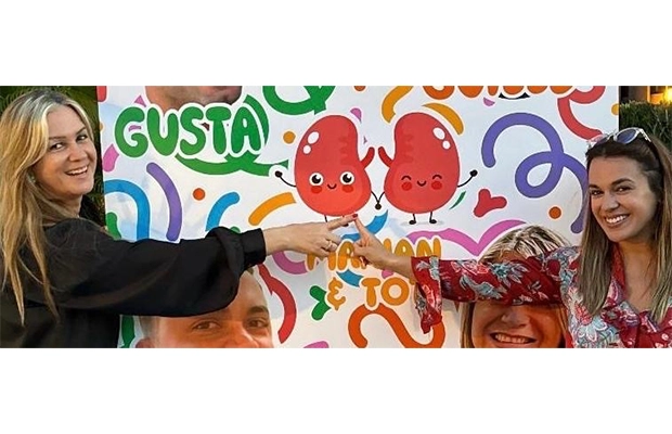 Two women posing and smiling next to a colorful poster