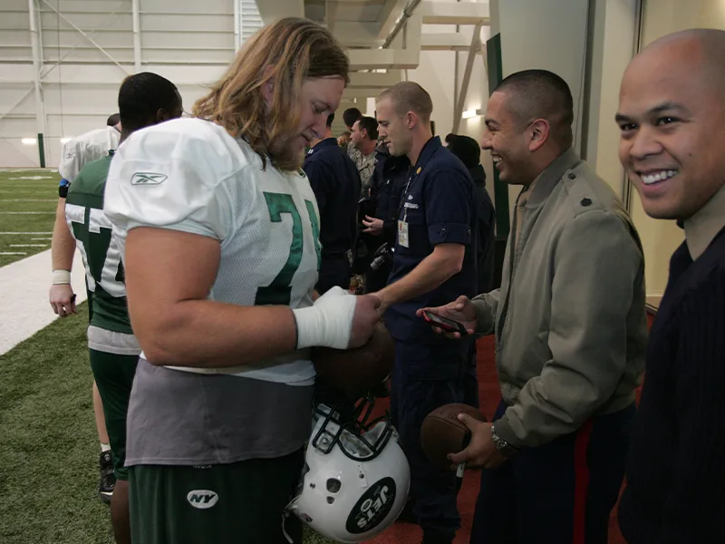 American football player signing autographs for a line of people