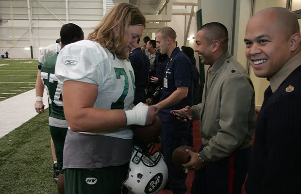 American football player signing autographs for a line of people