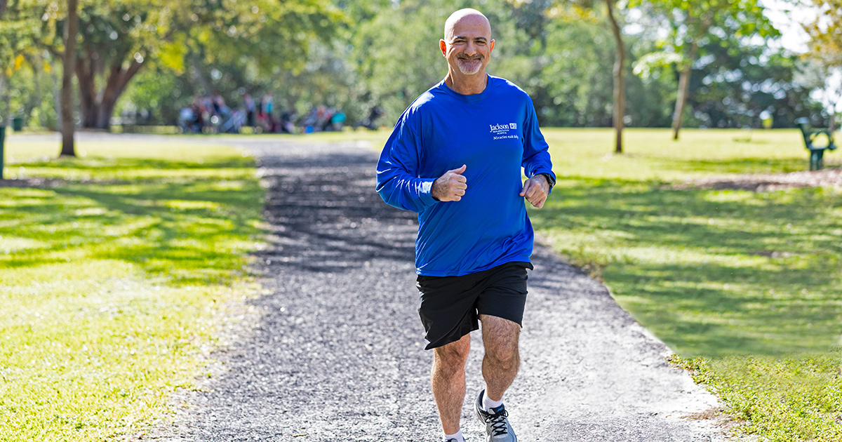 Ed Navarro running outside on a trail run, he is wearing a long sleeve blue shirt and black shorts