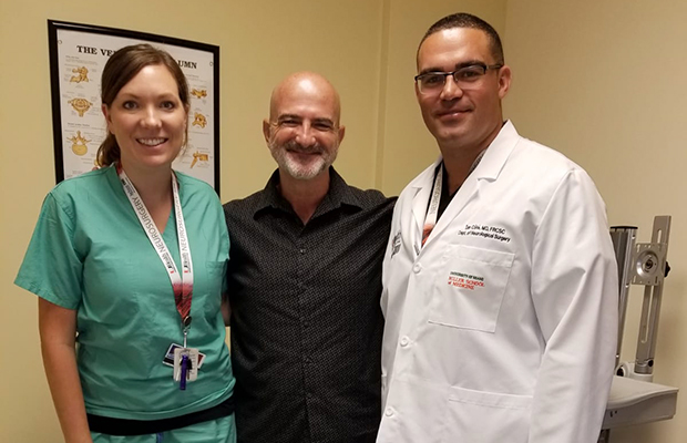 Ed Navarro standing and smiling next to two Jackson Health System employees
