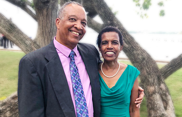 Edgerton McIntosh and his wife, Thelma McIntosh, standing and smiling in front of a tree and water backdrop