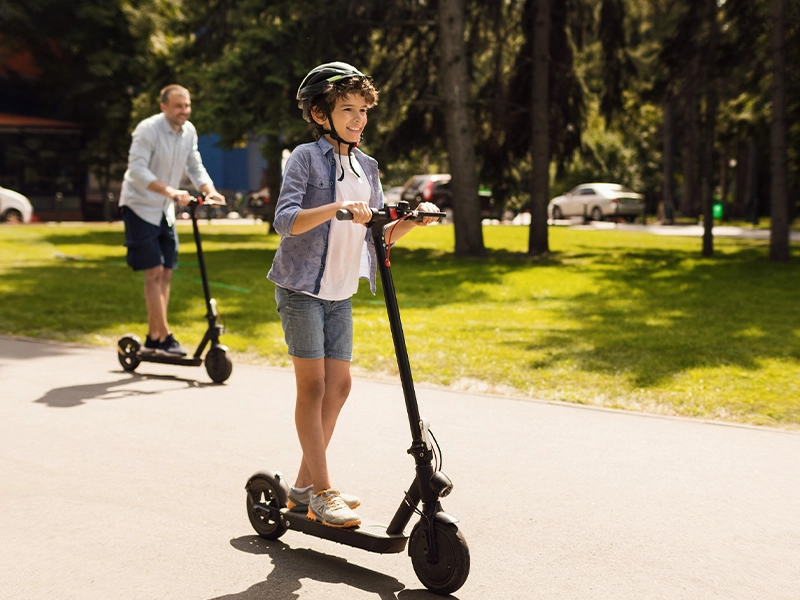 Man and boy riding electric skateboards in the park