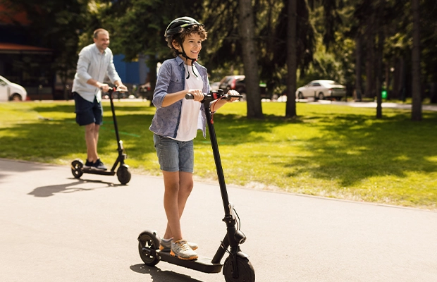 Man and boy riding electric skateboards in the park