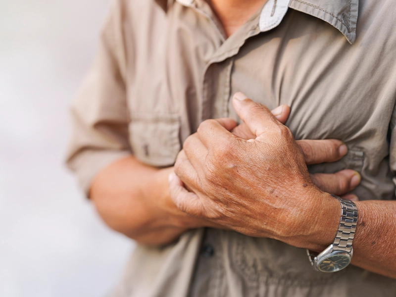Close-up of a man's hands holding his chest as if he were about to have a heart attack