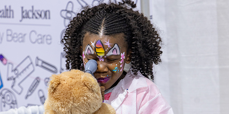 A young girl playing with a teddy bear